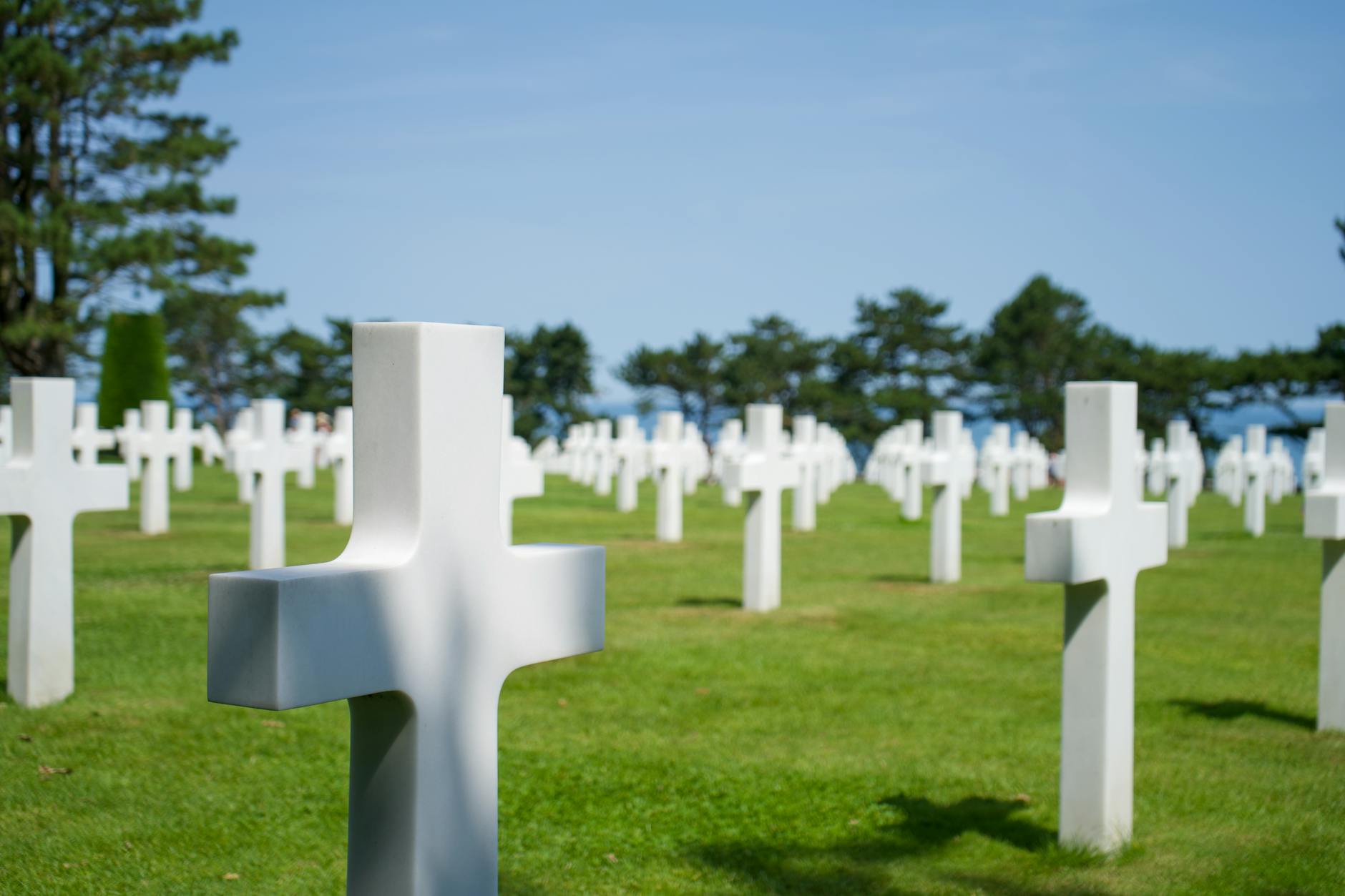 Rows of white crosses at the Normandy American Cemetery under a clear blue sky