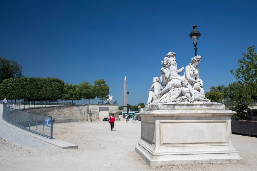 Obelisk and statues at Place de la Concorde under blue sky