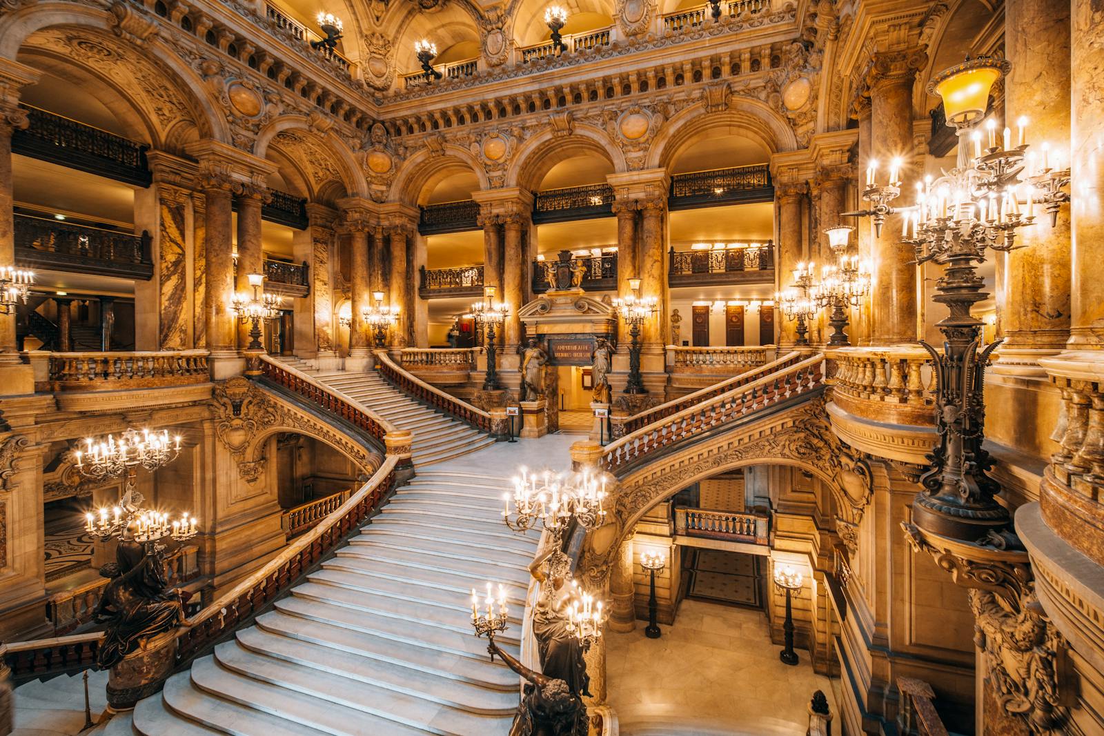 Elegant opera house staircase lit by ornate chandeliers at the Palais Garnier