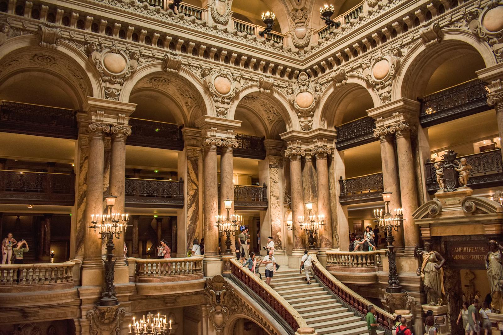 Interior view of a Palais Garnier staircase with sculptures and marble columns