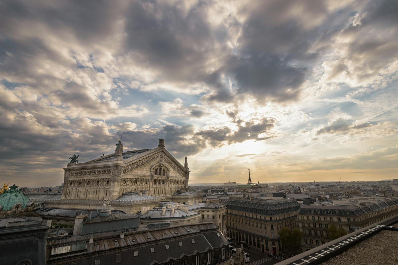 Palais Garnier framed against a sunset with the Eiffel Tower in the distance