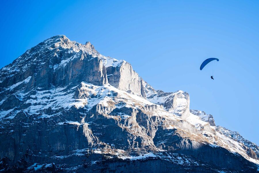 Paraglider soaring over alpine mountains