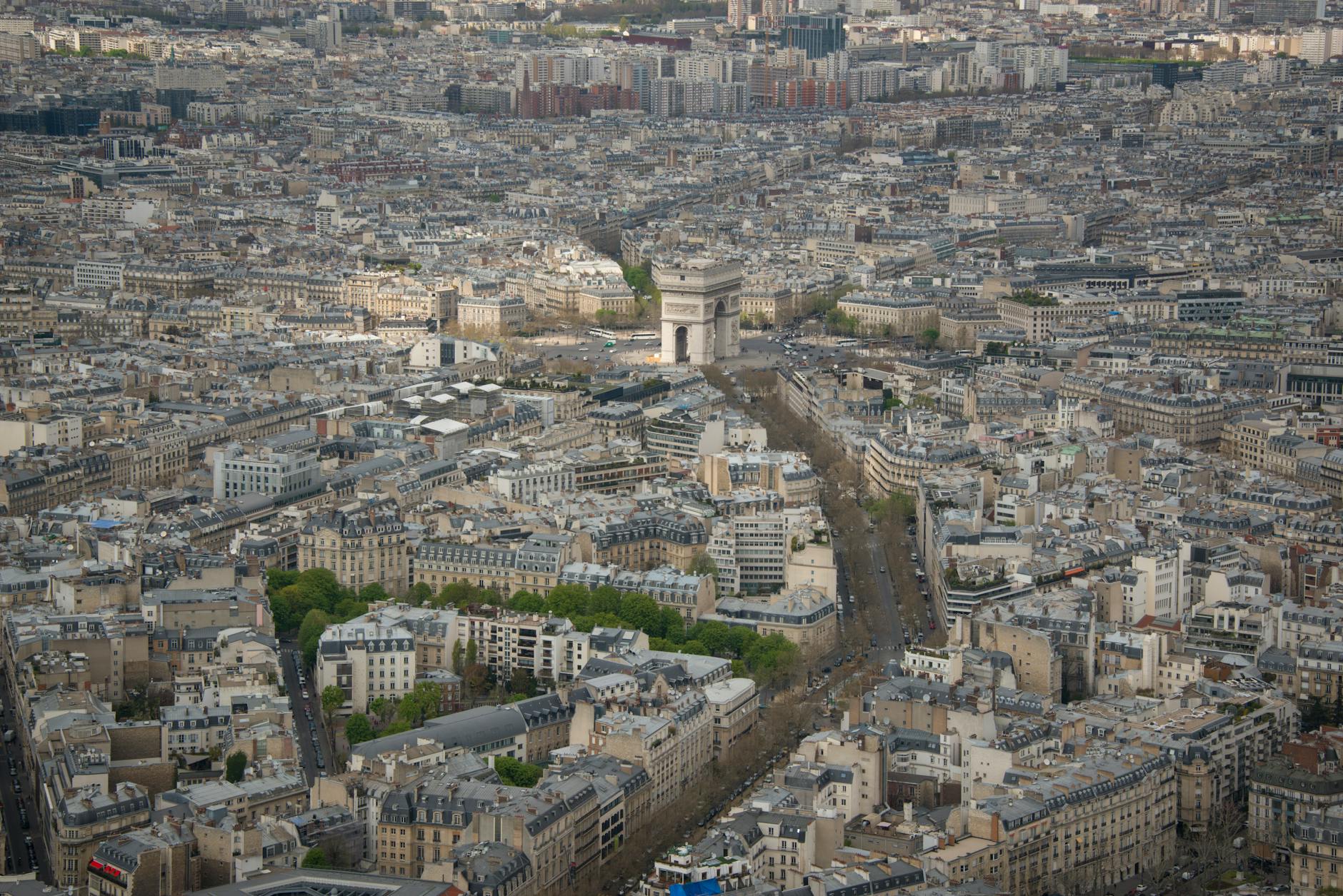 An aerial cityscape of Paris featuring the Arc de Triomphe roundabout