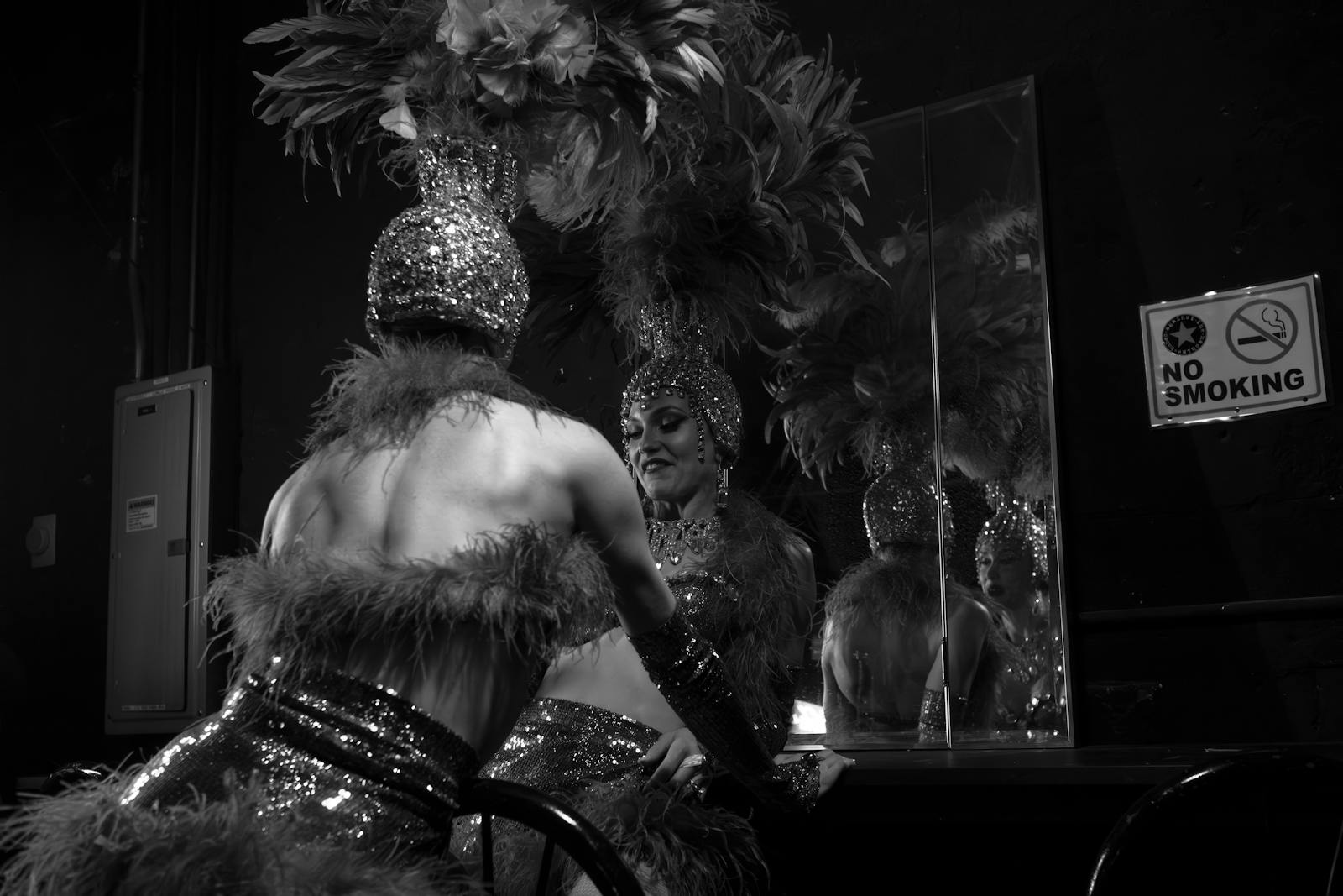 Cabaret dancer in a feathered headdress preparing in front of a mirror backstage