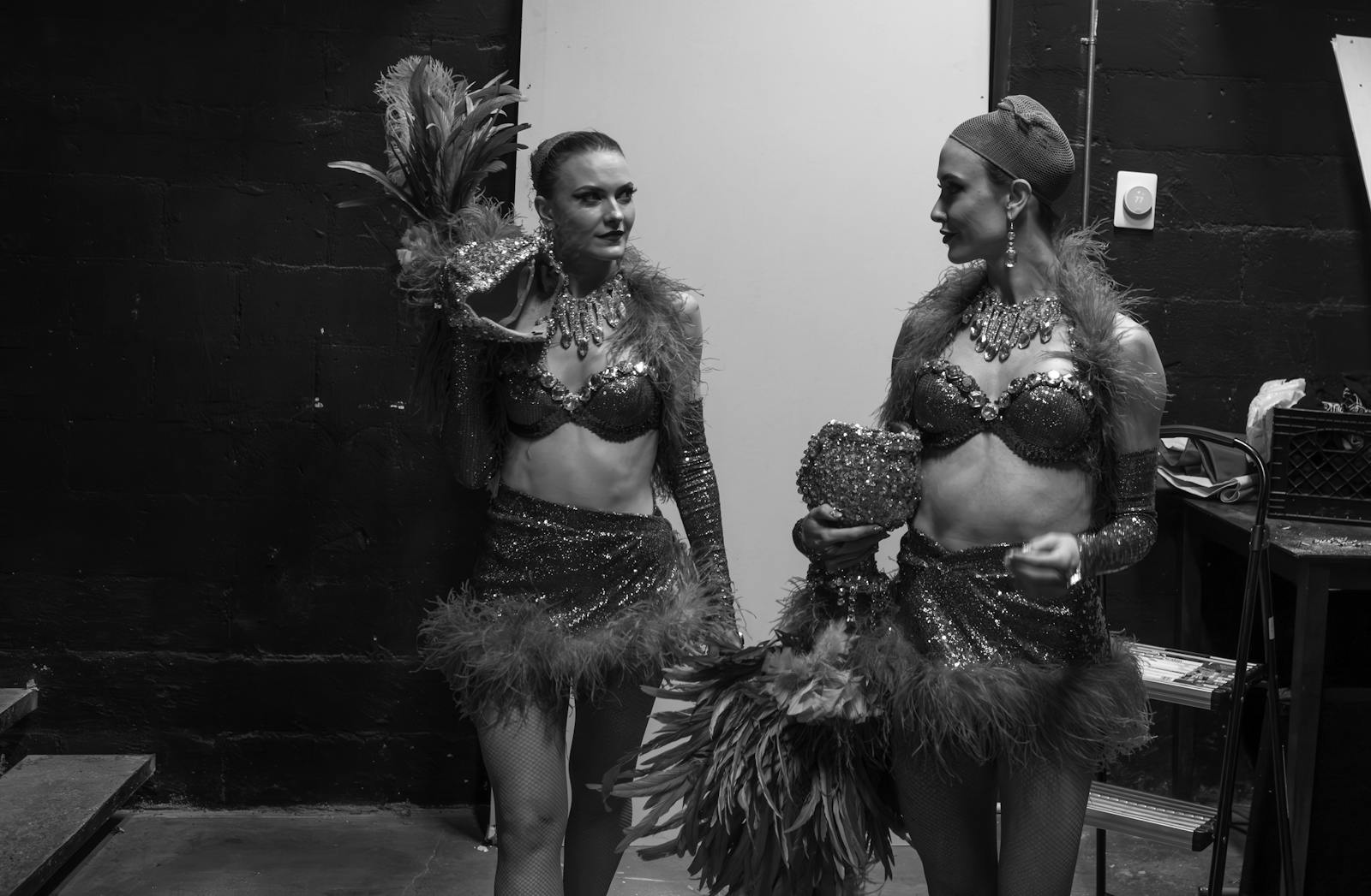 Two cabaret dancers in sparkling costumes backstage at a Paris revue in black and white