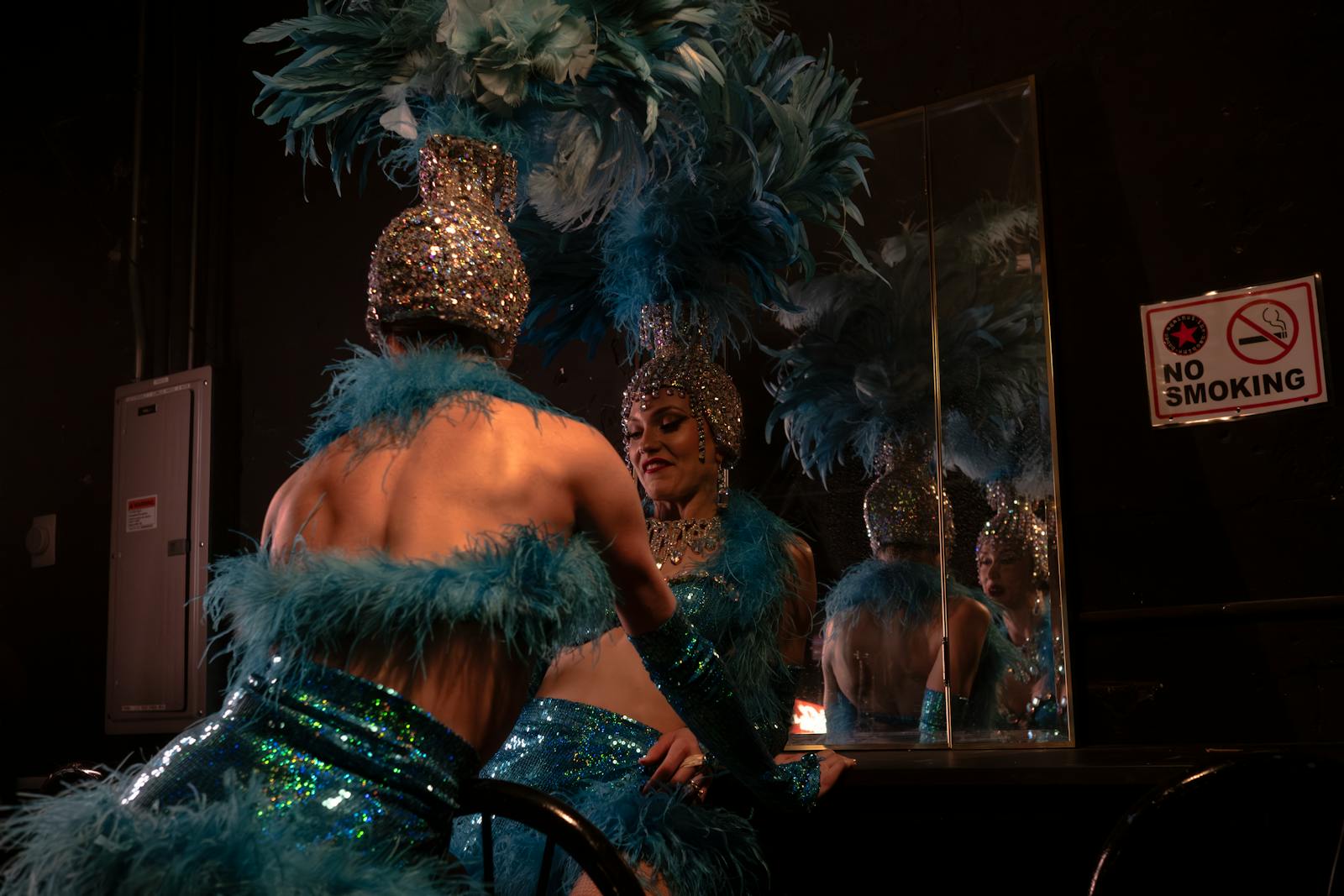 Cabaret showgirl in elaborate feathered and sequined costume preparing backstage