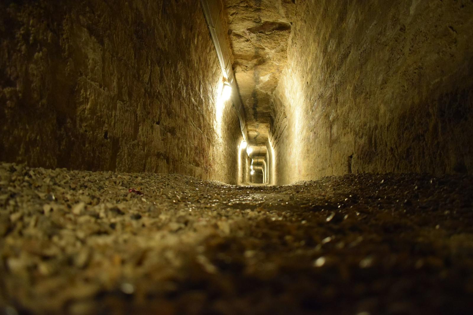 Moody dimly lit stone tunnel inside the Paris Catacombs