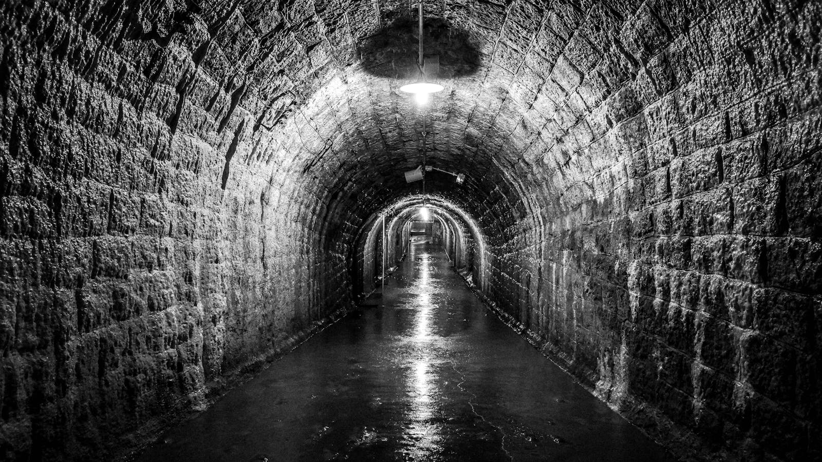 Dimly lit stone-walled tunnel inside the Paris Catacombs
