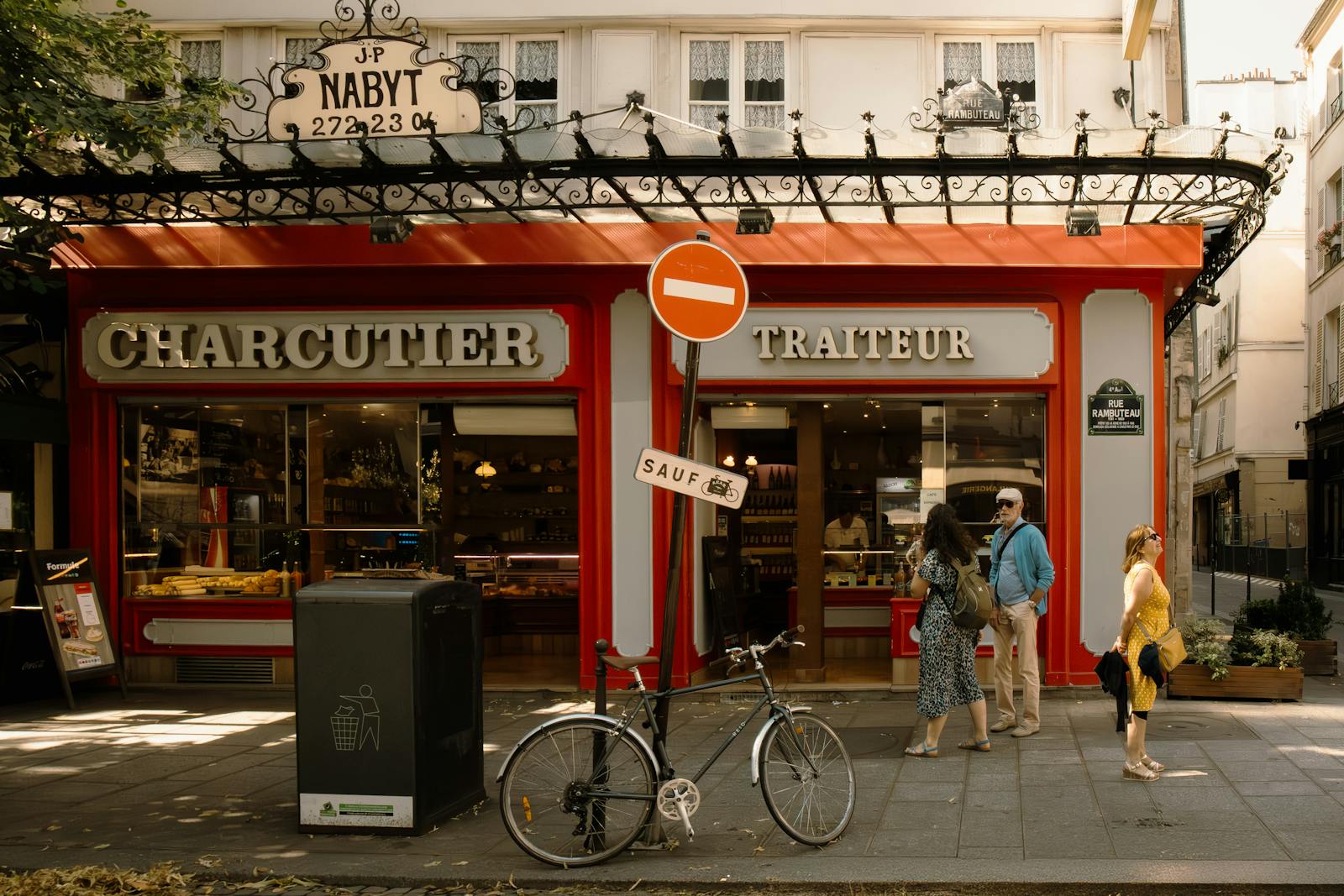 Parisian charcuterie shop front with pedestrians passing in warm afternoon light