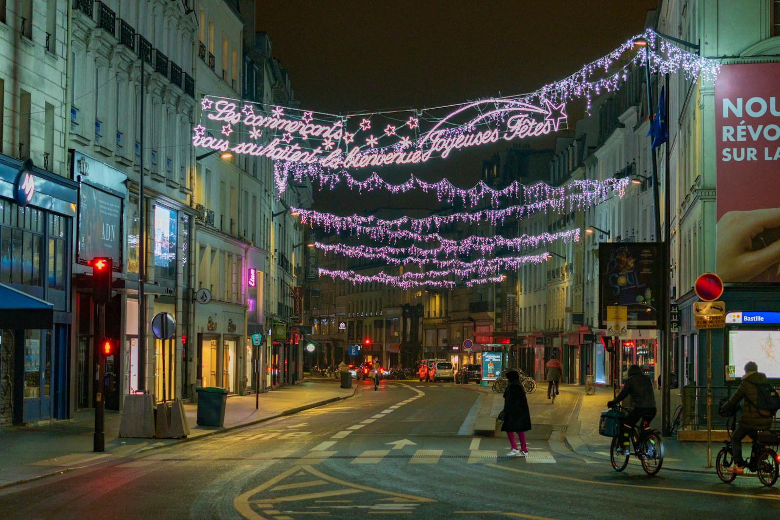 Illuminated streets of Paris with cyclists and pedestrians under festive lights