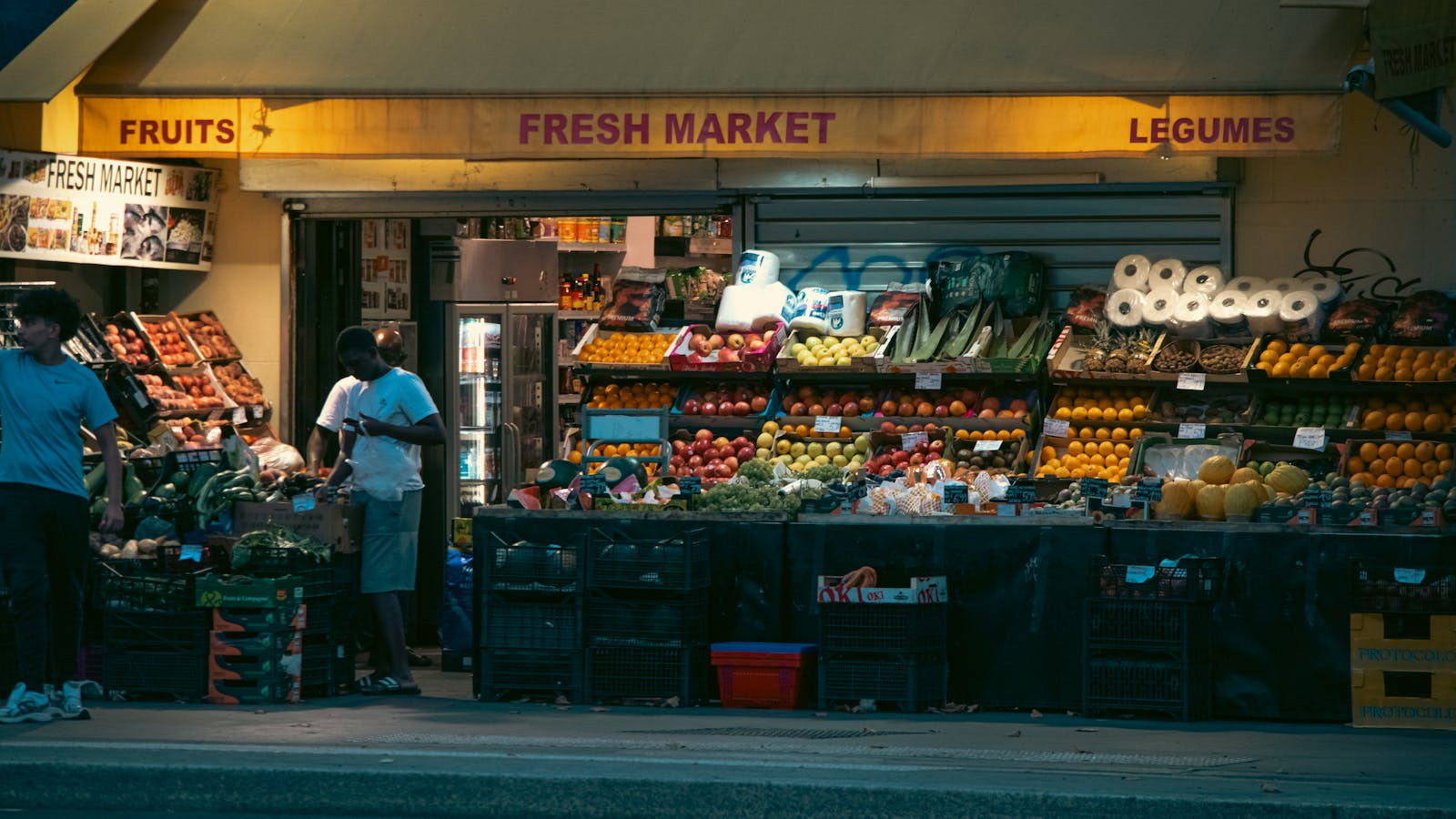 Paris neighborhood market with fresh produce displayed under evening lights