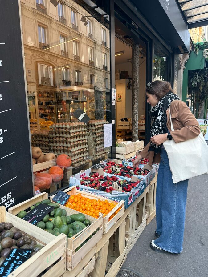 Woman examining fresh produce at a Parisian market