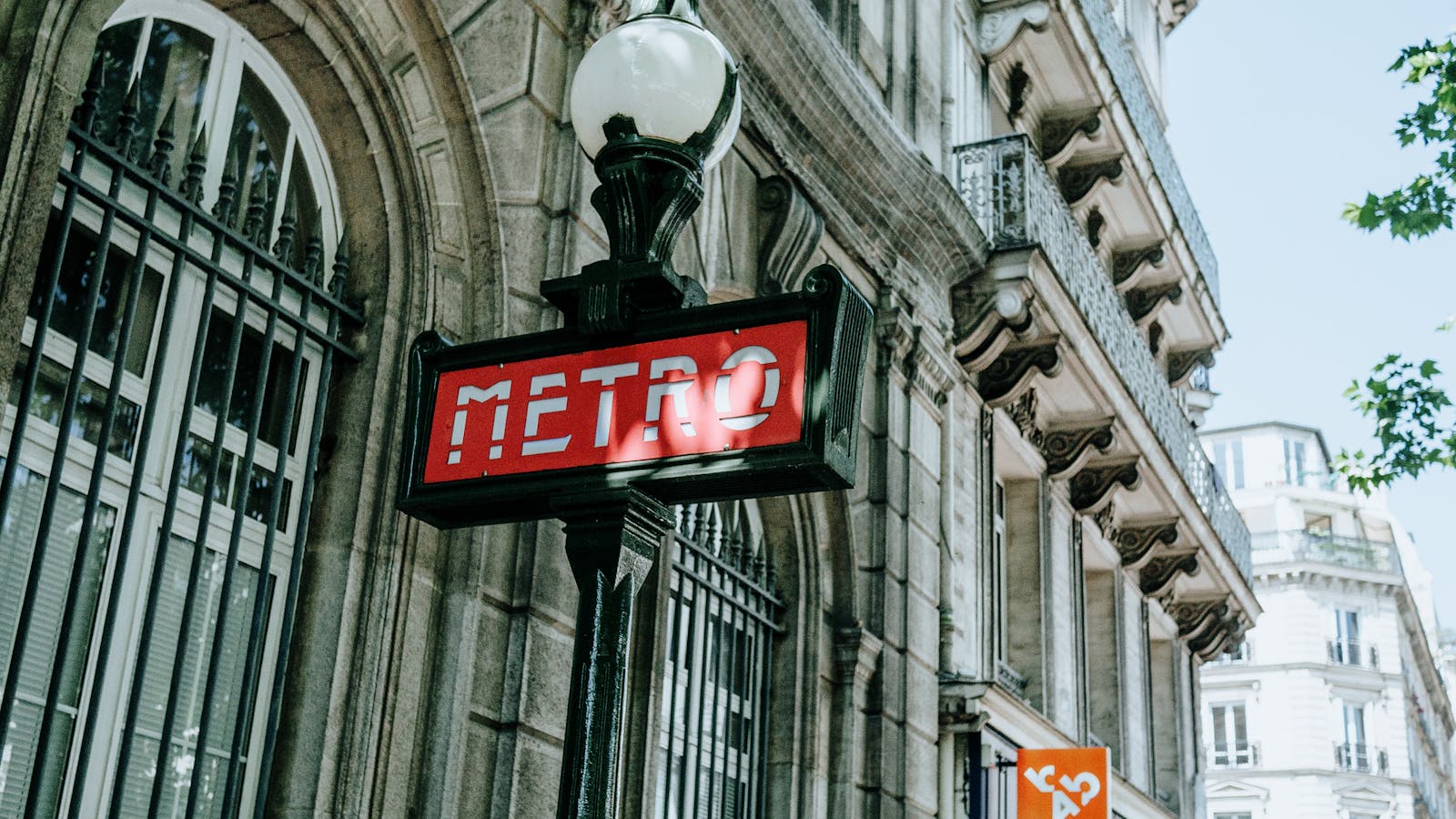 Iconic Paris Metro sign with classic Haussmann architecture in the background