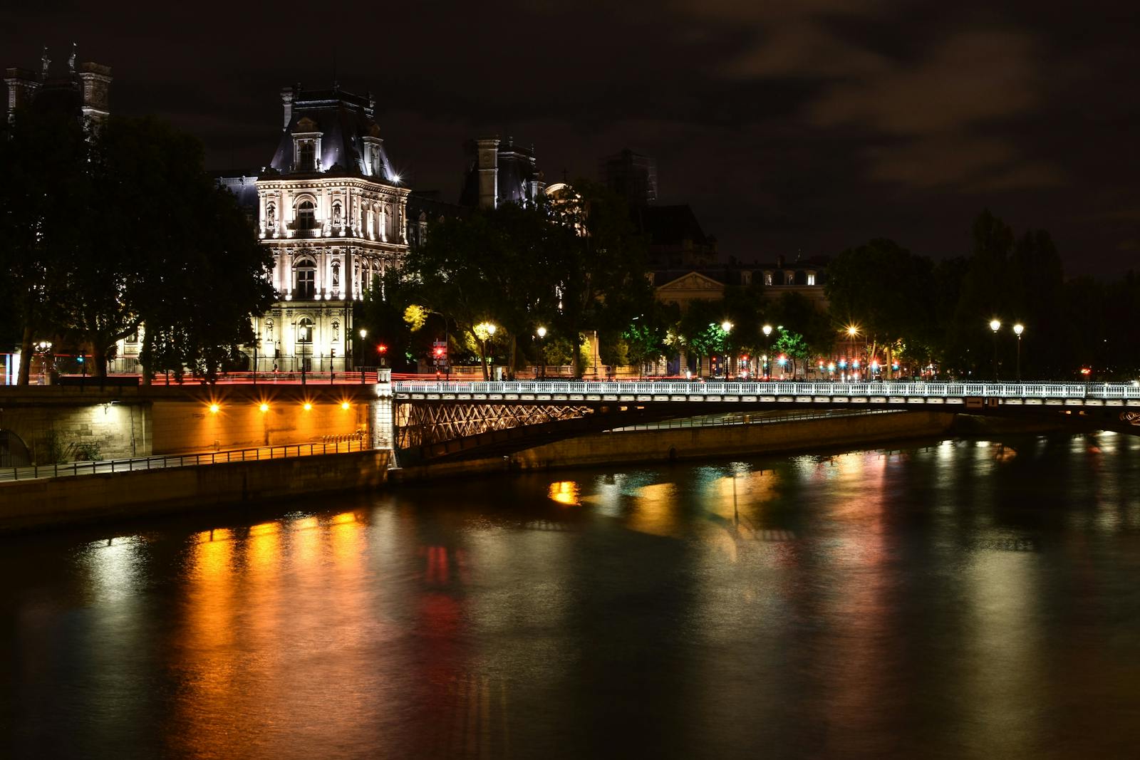 Night view of the illuminated Eiffel Tower reflecting on the Seine River