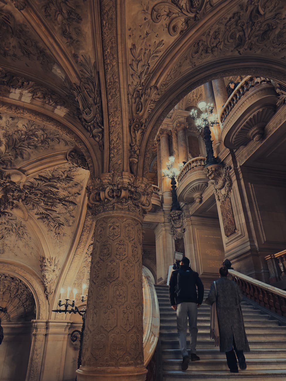Two visitors ascending the ornate staircase in Paris Opera House