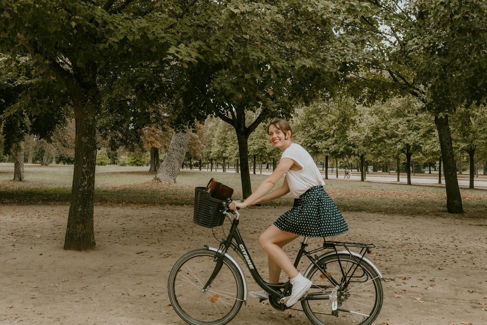 A young woman riding a bicycle in a beautiful Paris park during the day