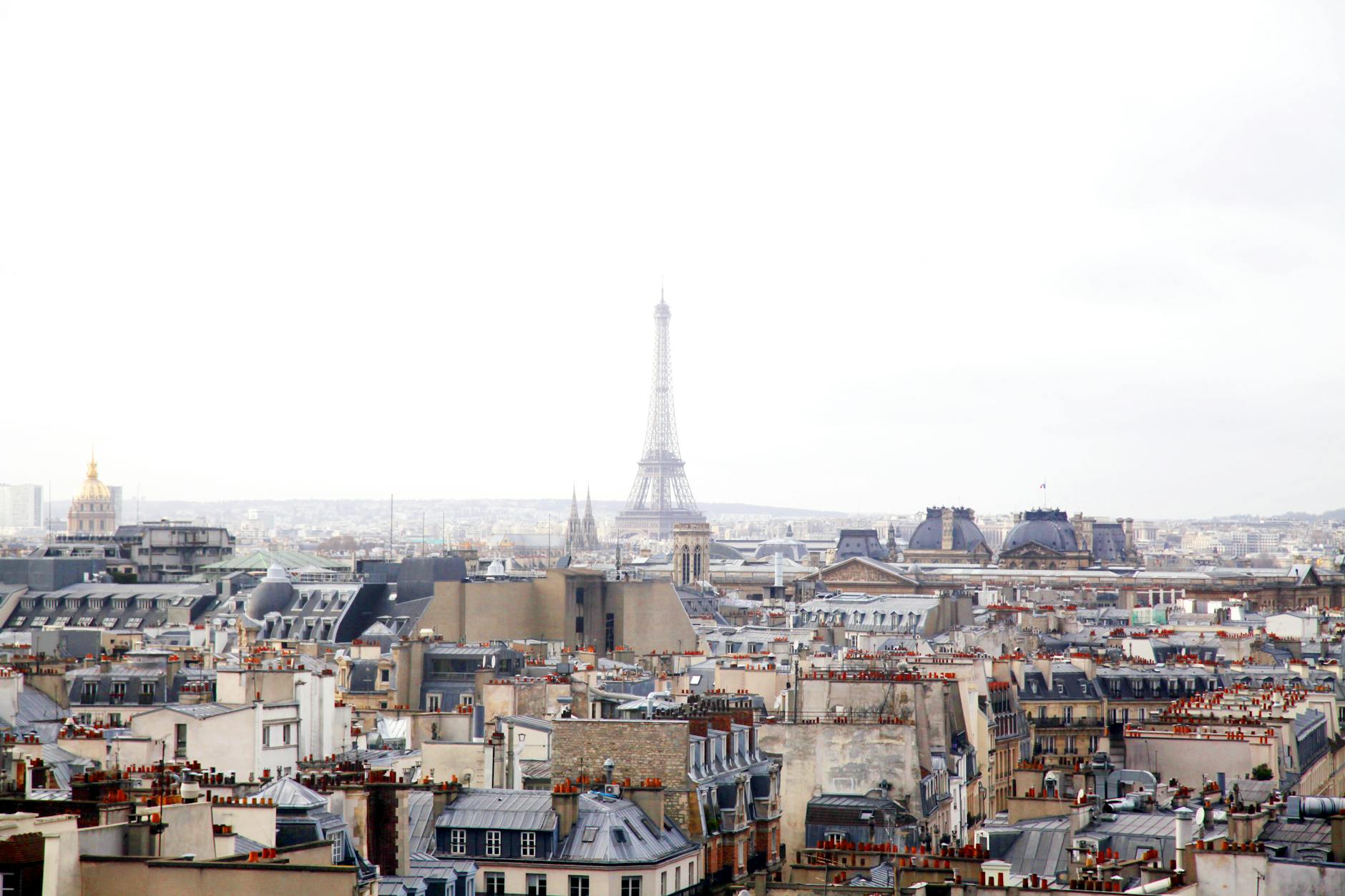 Paris rooftops with the Eiffel Tower rising behind chimneys and mansard roofs