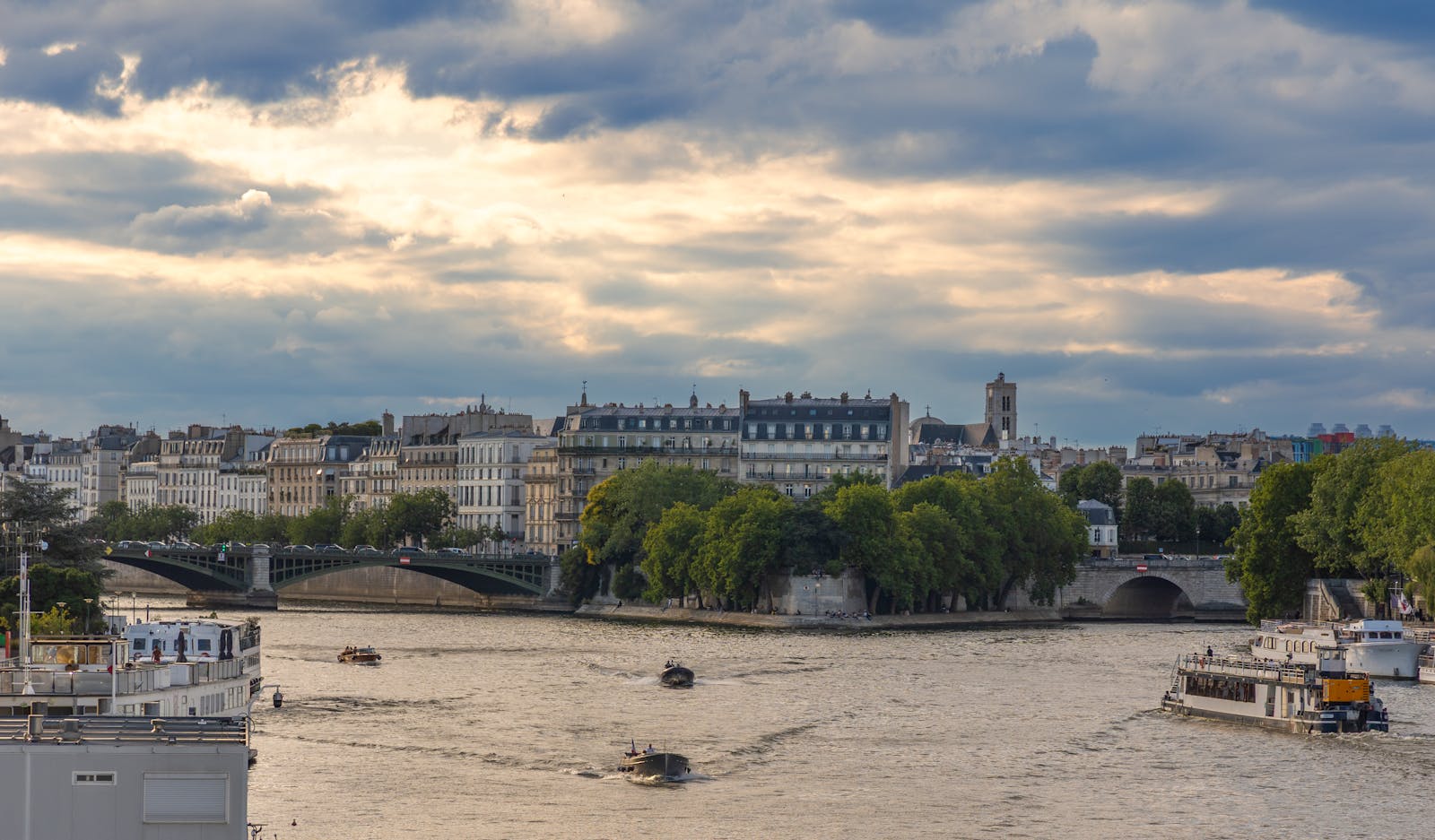 Paris Seine riverboats with iconic architecture under a cloudy sky