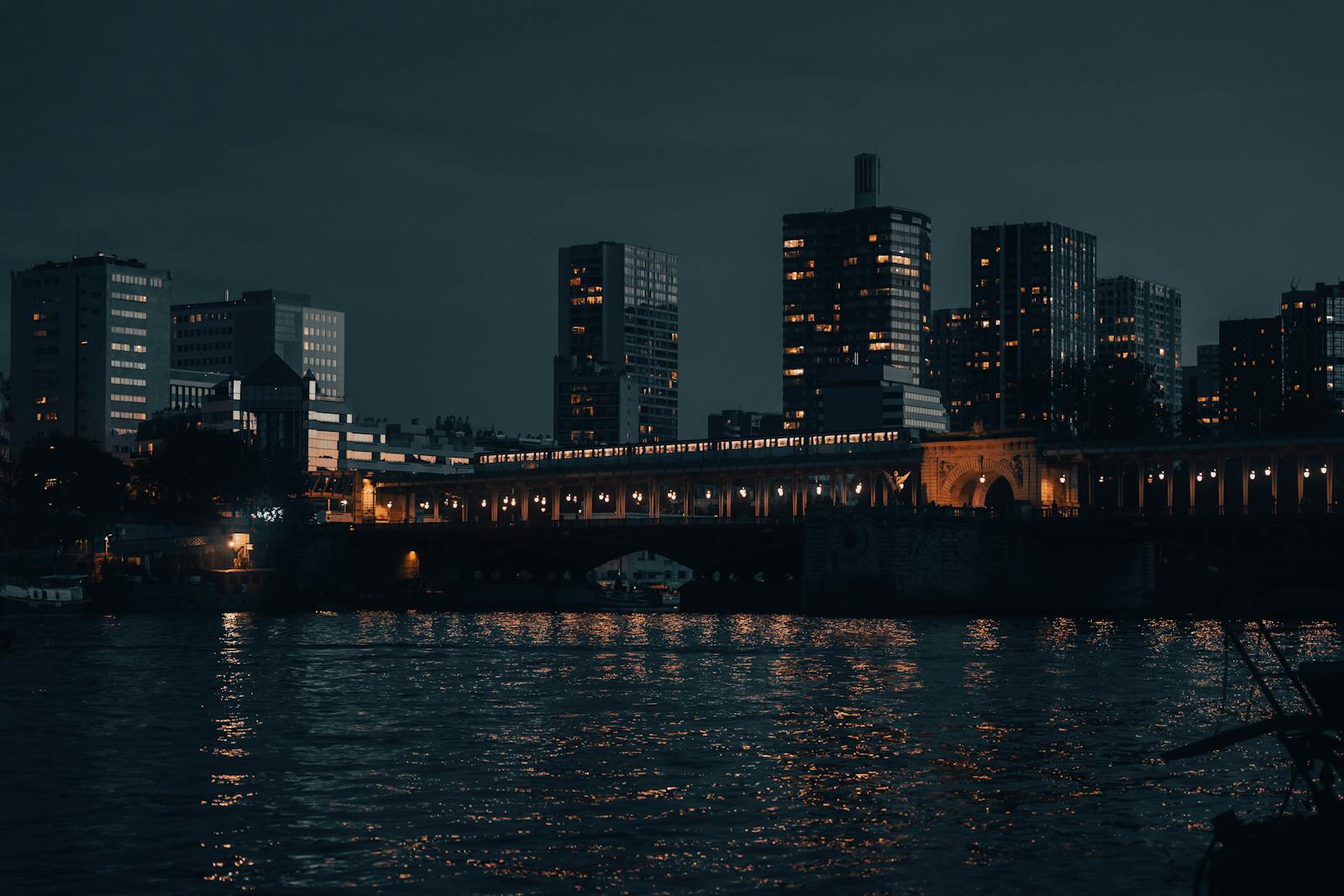 Paris skyline reflecting on the Seine River at night with illuminated buildings