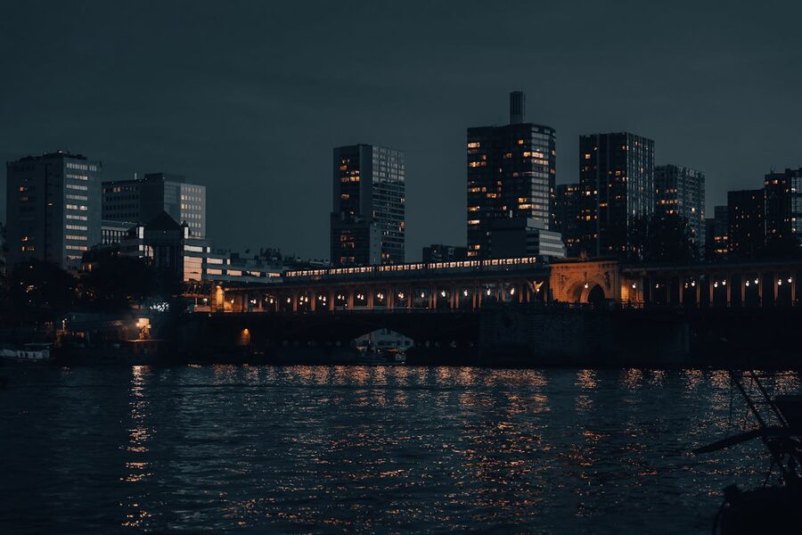 Nighttime Paris skyline with illuminated buildings reflected on the Seine