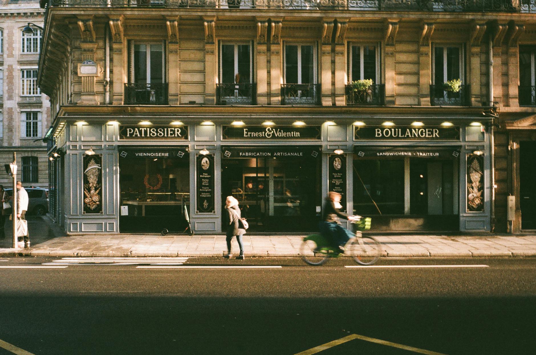 Paris street with classic French bakery and cyclist passing by