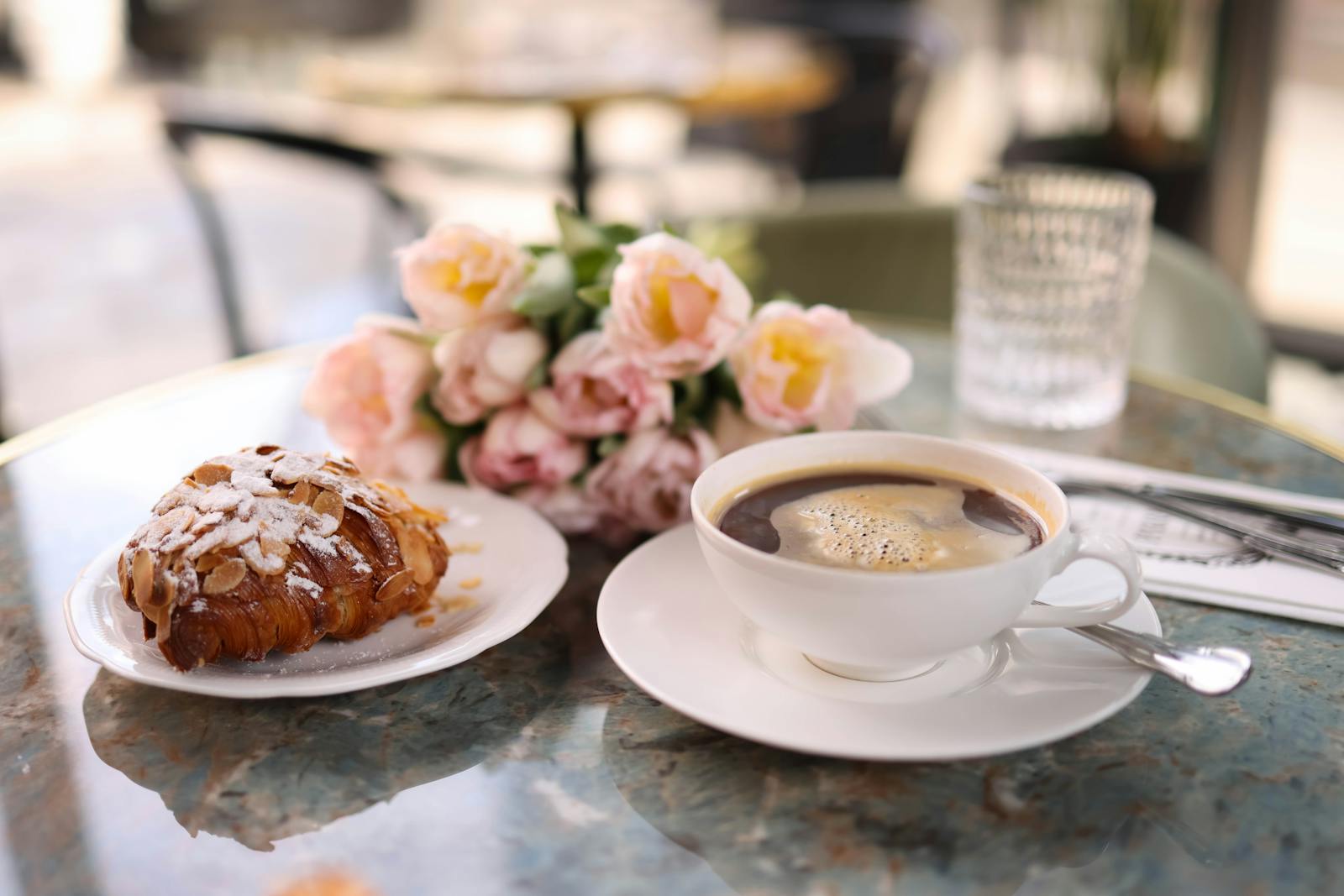 Parisian café table with a fresh croissant, coffee, and a vase of flowers
