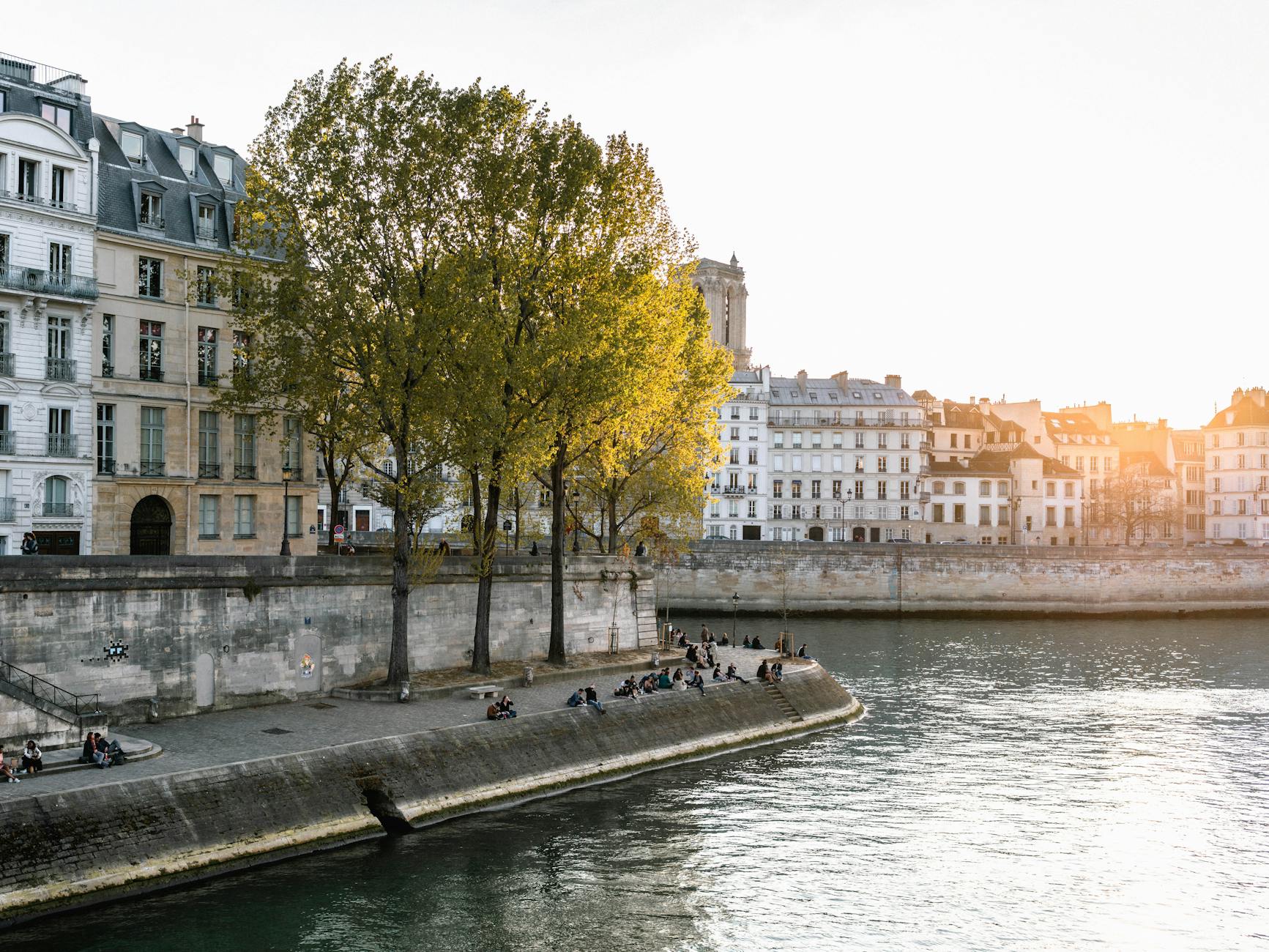 People relaxing on the Seine riverbank with classic Paris architecture behind