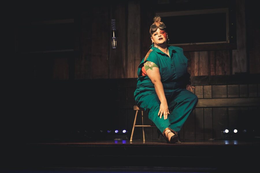 Performer in blue attire on a dimly lit cabaret stage