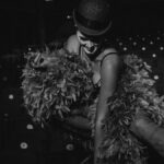 Cabaret performer in feathers exuding glamour in black and white