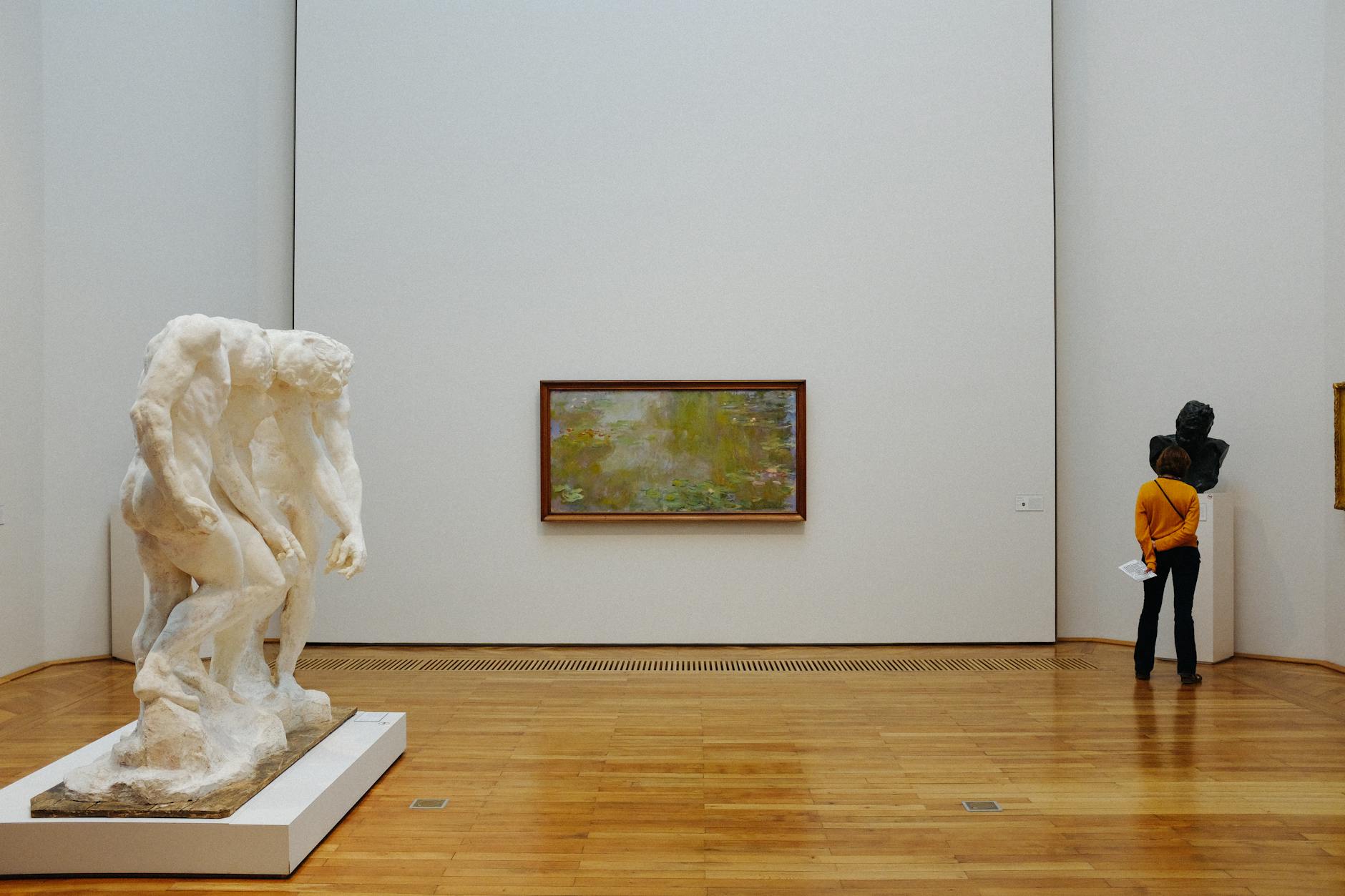 A person admires art in a modern gallery featuring sculpture and painting