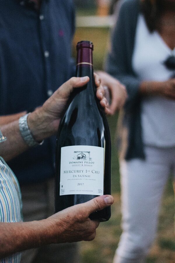 Person holding a Burgundy wine bottle outdoors