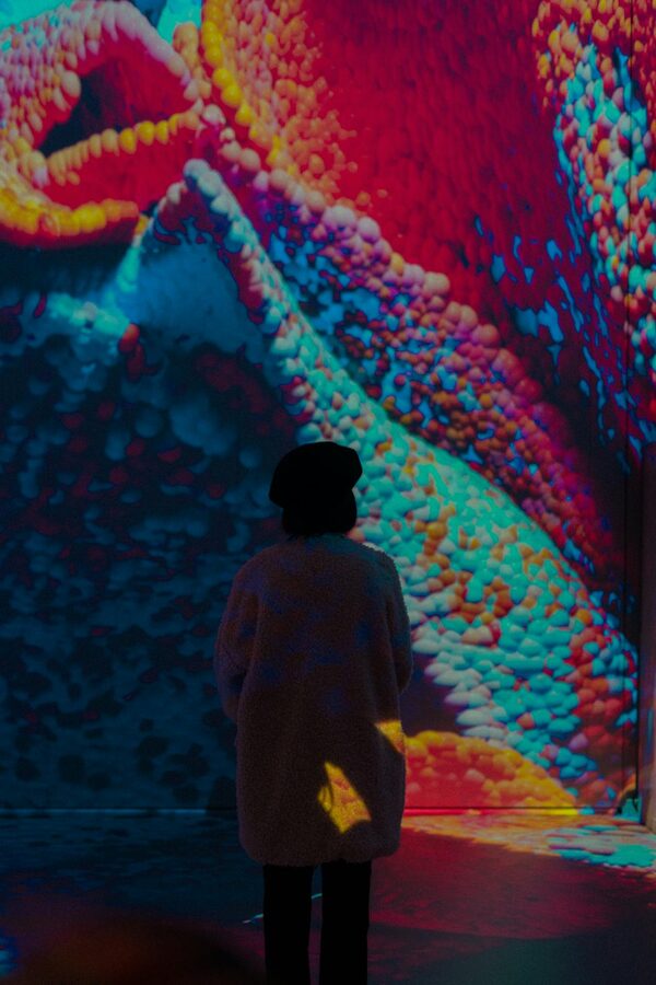 Person standing mesmerized by a colourful digital art installation