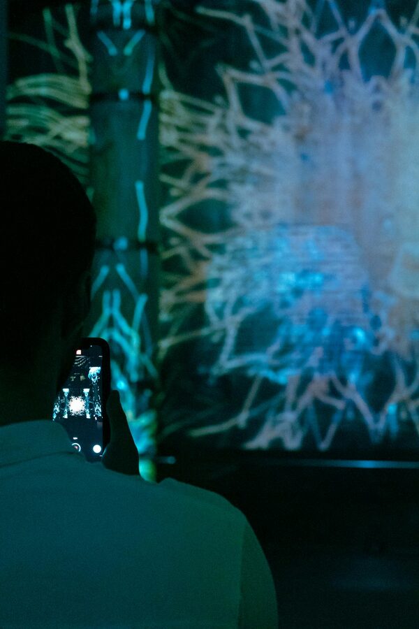 Person photographing a digital art installation using a smartphone