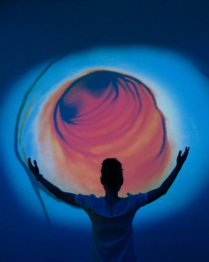 Person silhouetted against a swirling abstract colour projection