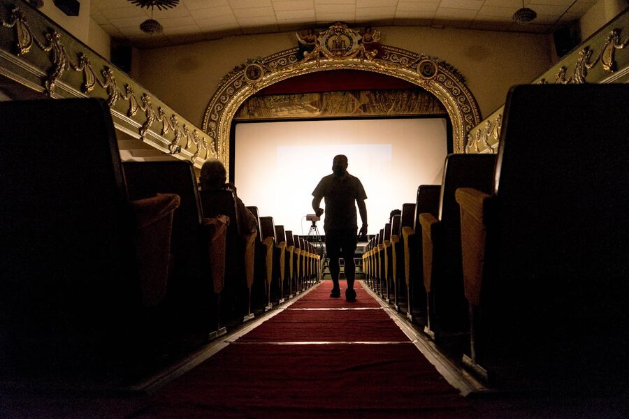 Person walking down an aisle in a vintage theater with ornate decor