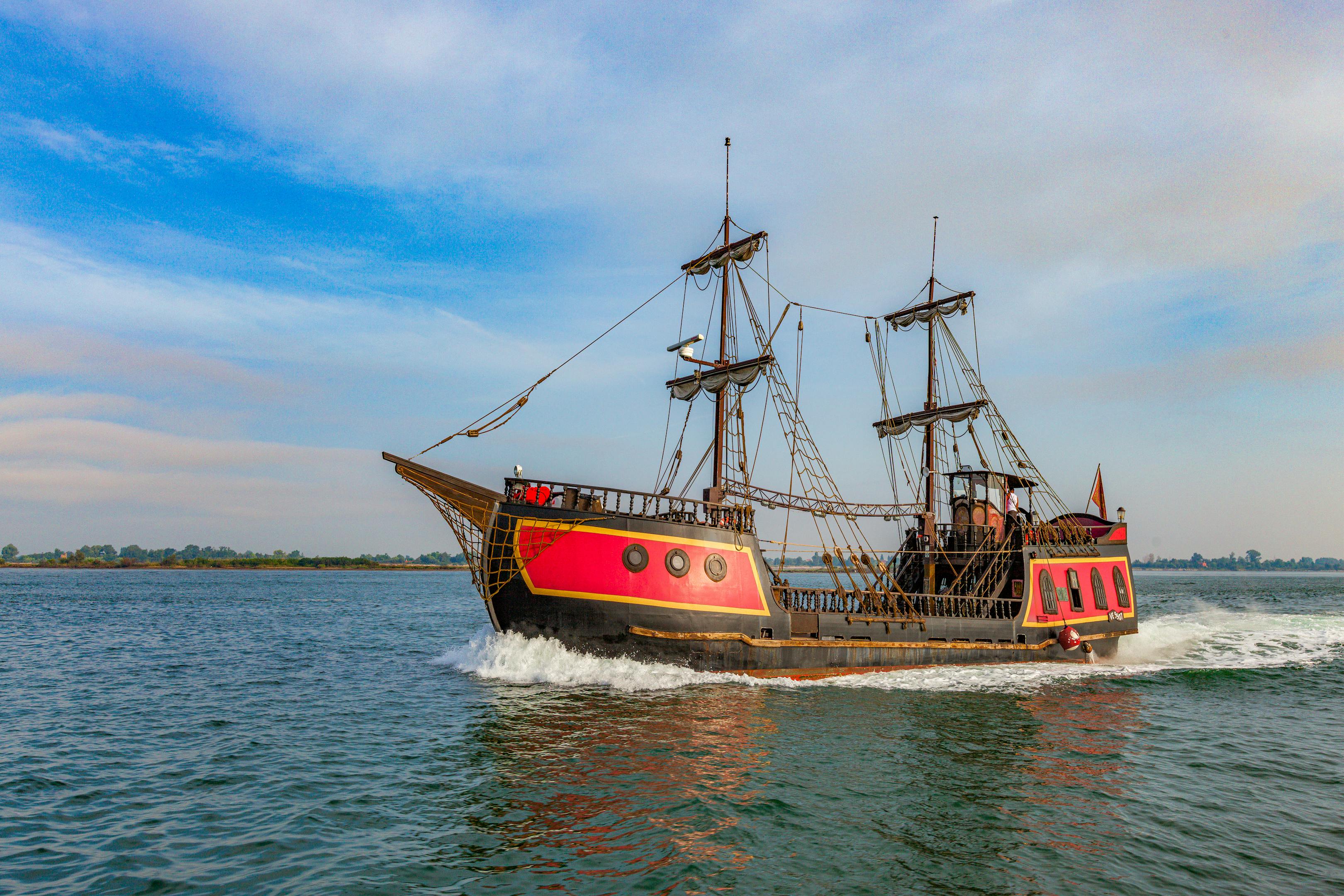 A vibrant pirate ship sails on a clear day, showcasing its vintage wooden structure and colorful design