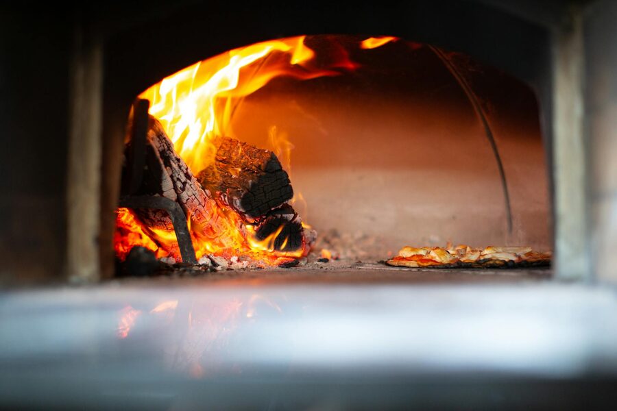 Pizza baking with open flames in a wood-fired oven