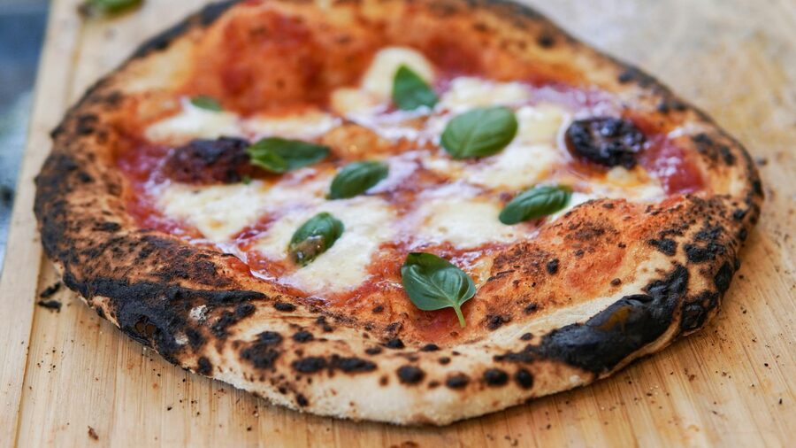 Wood-fired Margherita pizza on a wooden surface