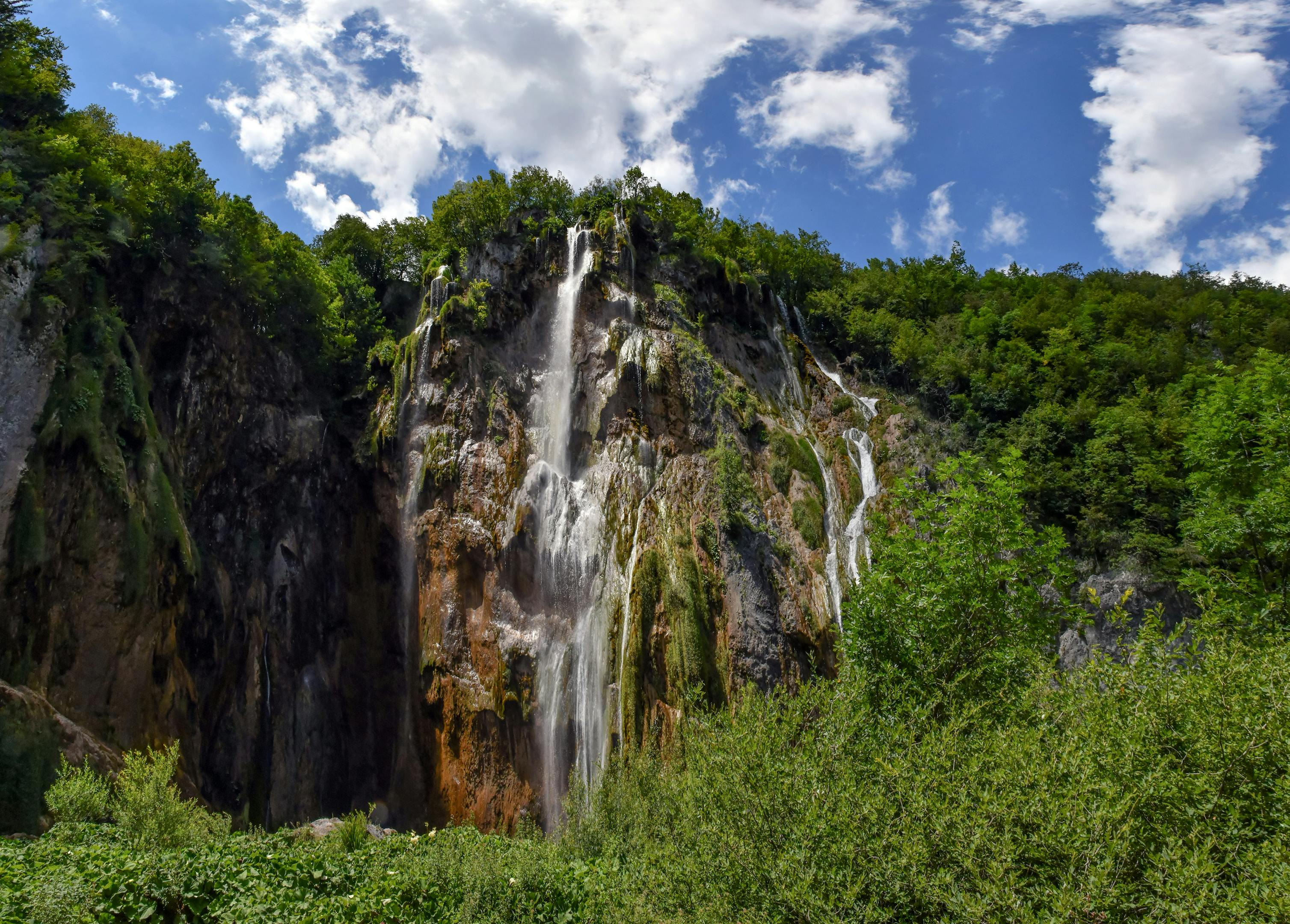 Scenic view of a towering waterfall in Plitvice Lakes under a vibrant sky