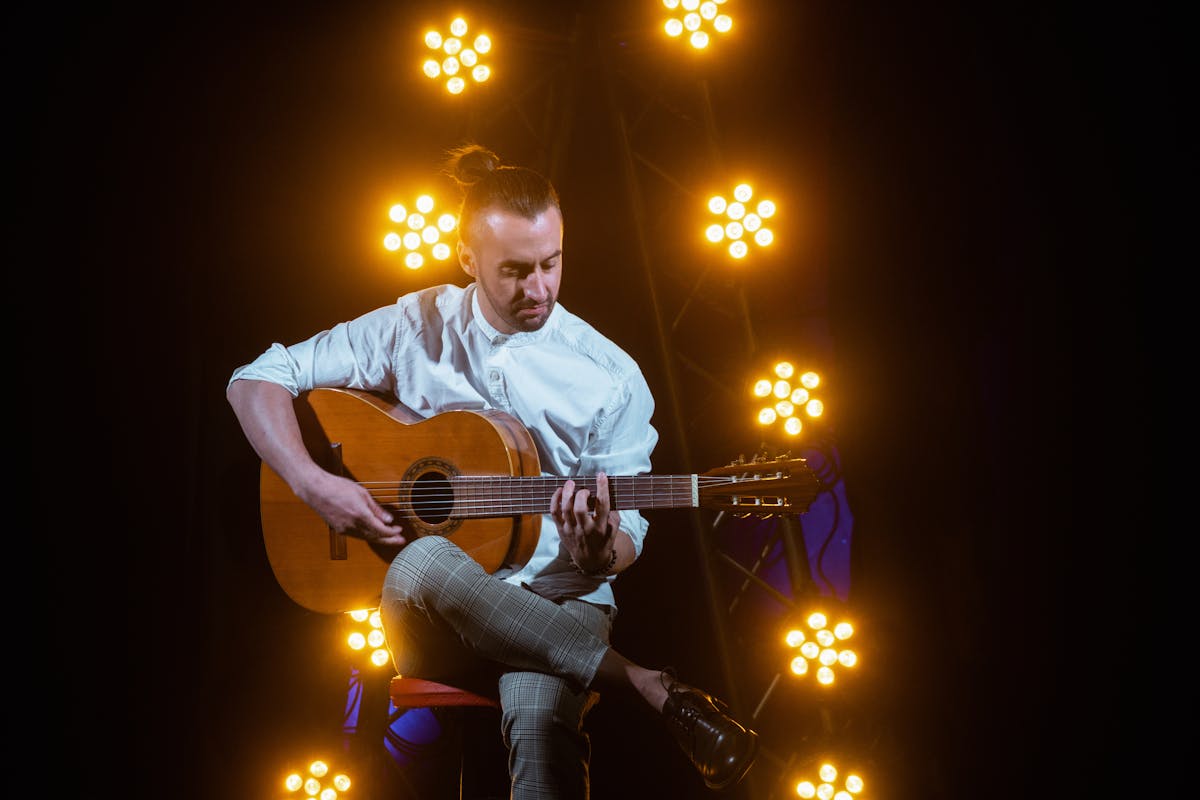 Musician playing acoustic guitar on stage during a fado performance