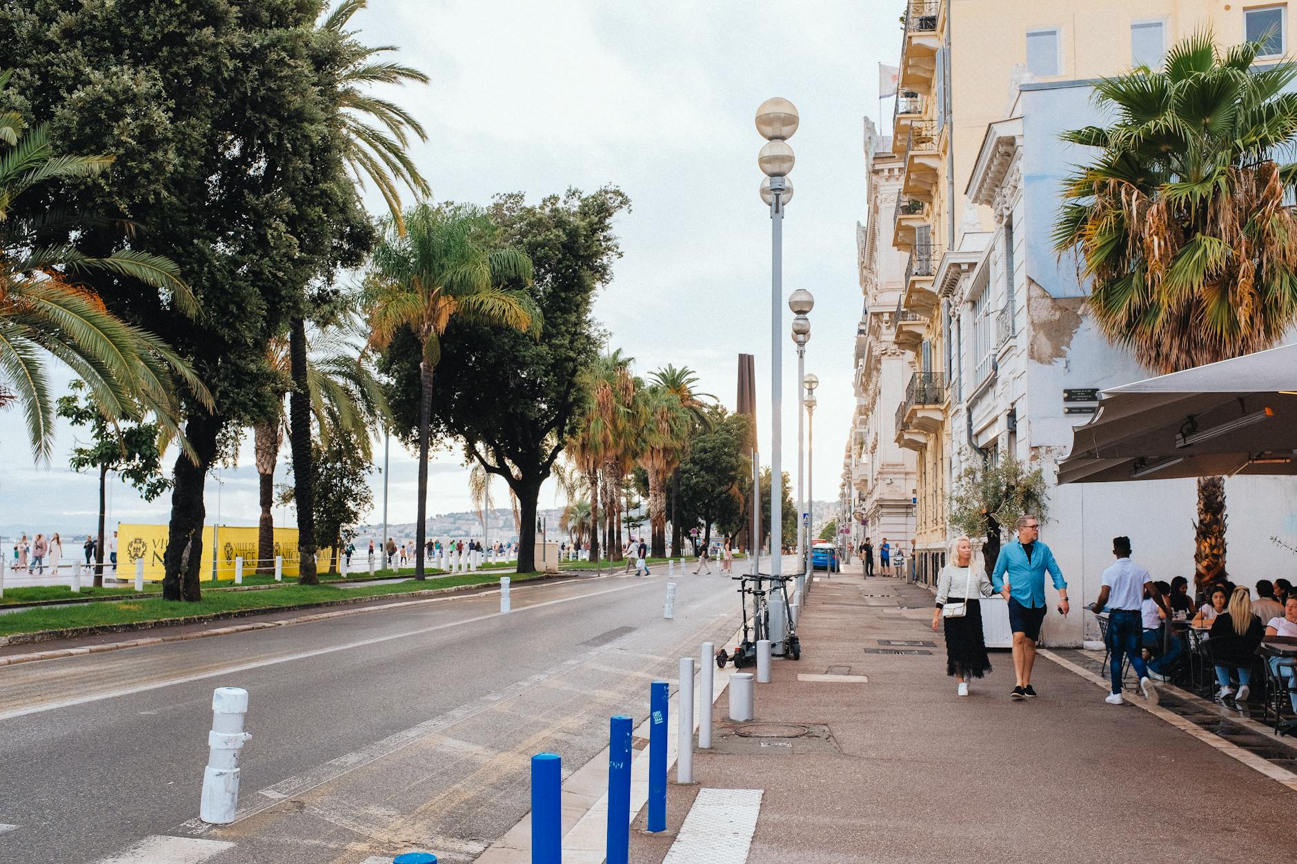 Sunny day on the Promenade des Anglais in Nice with people walking and cycling