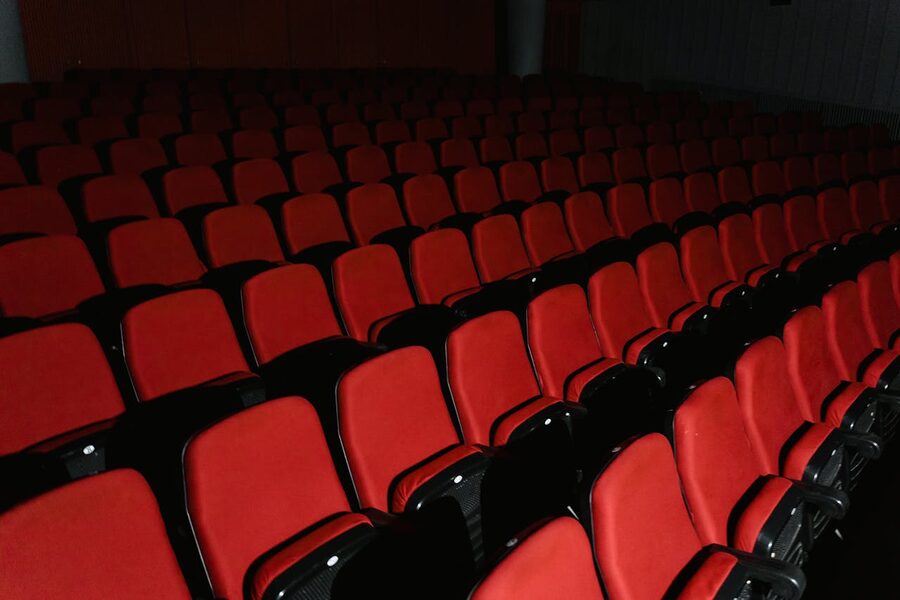 Empty red theater seats arranged in rows inside a cinema hall