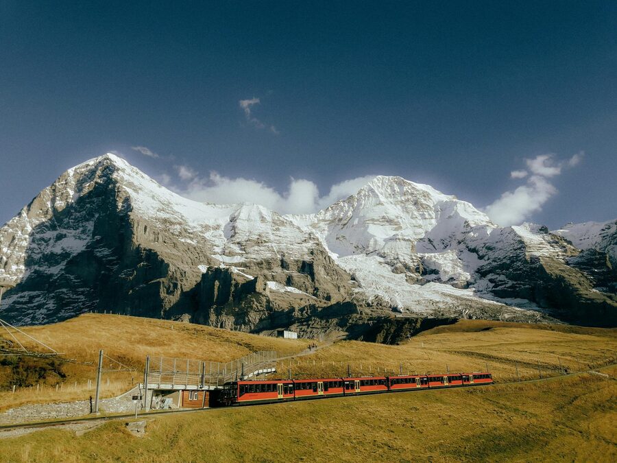 Red train traversing snowcapped Alps
