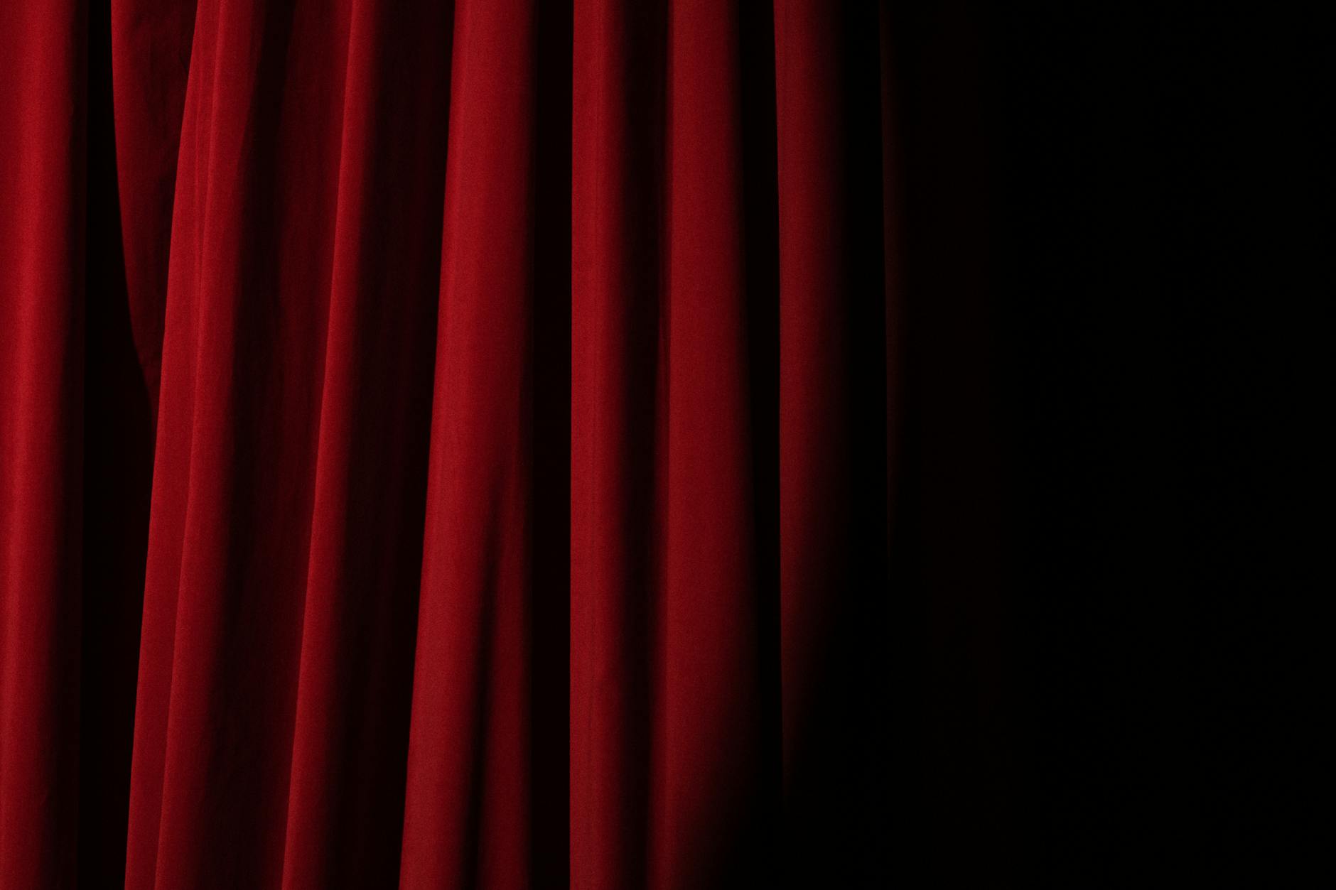 Dramatic red velvet theater curtain in warm light