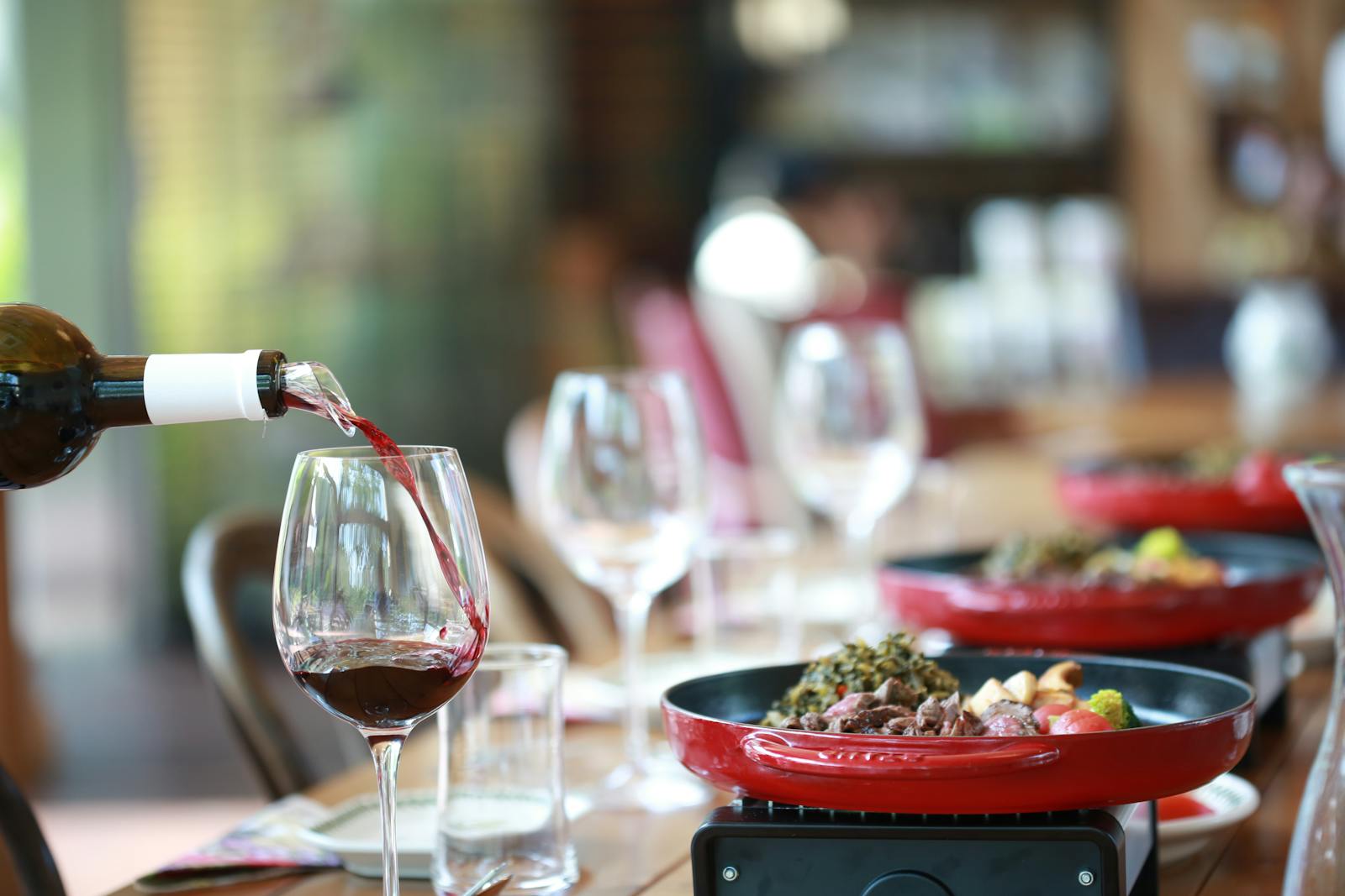 Red wine being poured into a glass at an elegant dinner setting