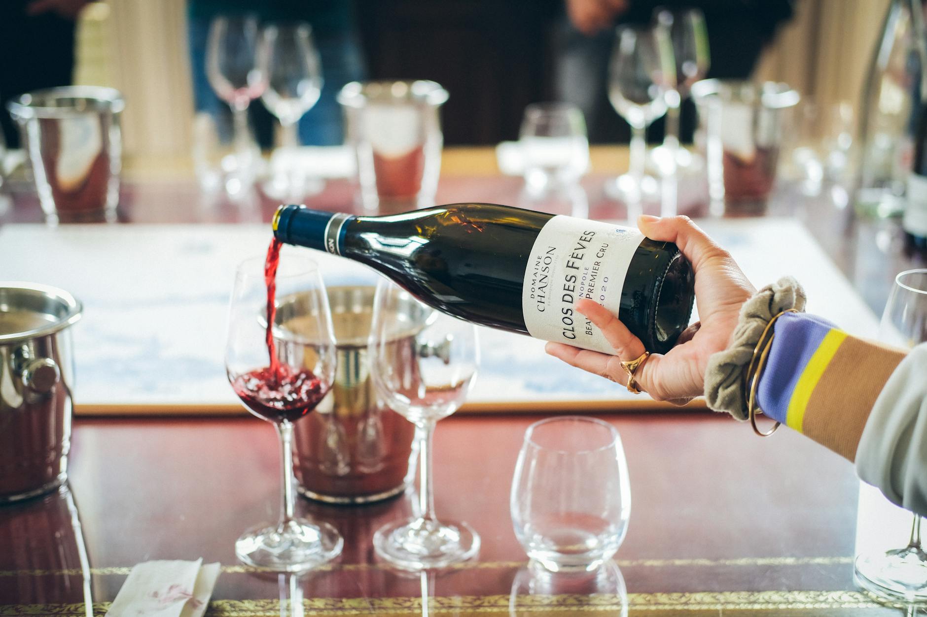 Red wine being poured into a glass on a dining table