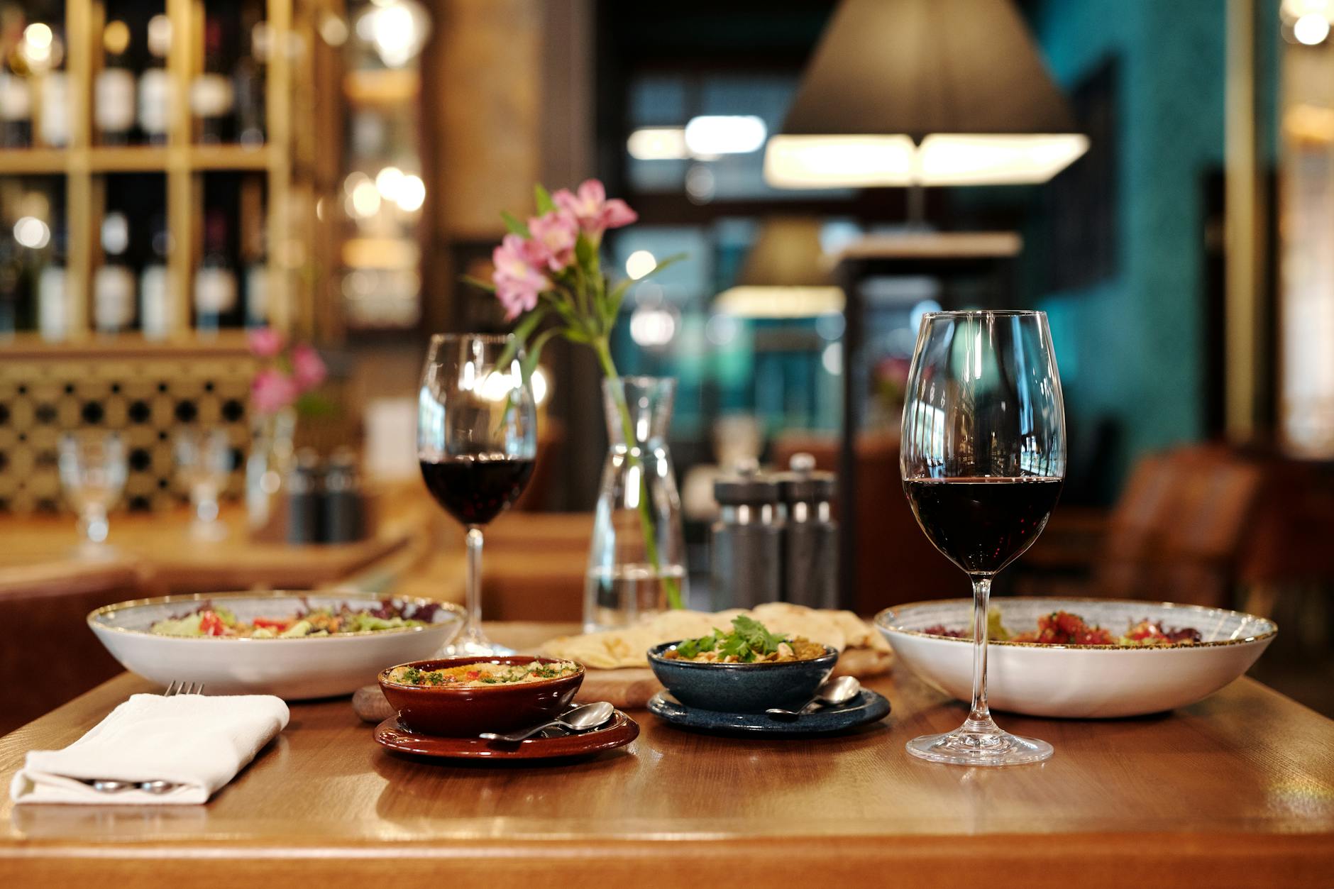 A meticulously arranged restaurant table setting with red wine and various appetizers