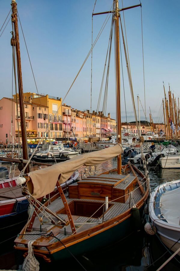 Wooden sailboats moored in Saint-Tropez Harbour at sunset with colourful buildings
