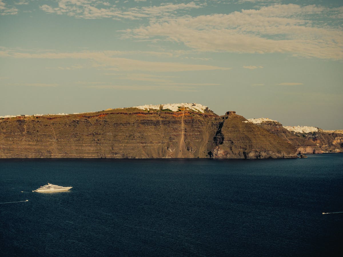 Santorini's steep coastline with a ship in the Aegean Sea