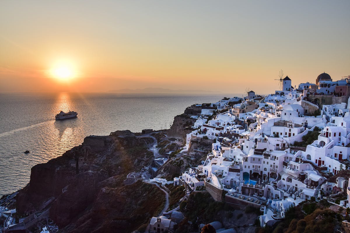 Sunset view of Santorini's whitewashed buildings and a cruise ship in the Aegean Sea